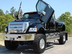 a large black truck parked on the side of a road with its doors open and it's hood up