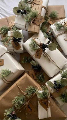 many wrapped presents are stacked on top of each other with evergreen leaves and pine cones