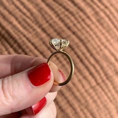 a woman's hand holding a gold ring with a diamond on the top and bottom