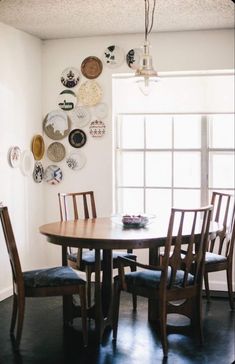 a dining room table and chairs with plates on the wall