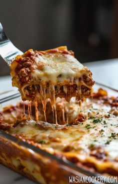 a slice of lasagna being lifted with a fork from a casserole dish