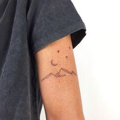 a person with a tattoo on their arm that has mountains and stars in the sky