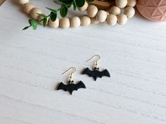 the bat earrings are on display next to a plant