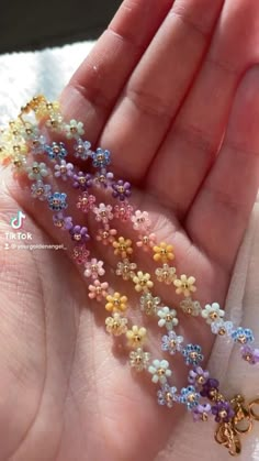 the tiny beads are being held in someone's hand and they are all different colors