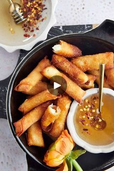 some food is in a black bowl on a table with other dishes and utensils