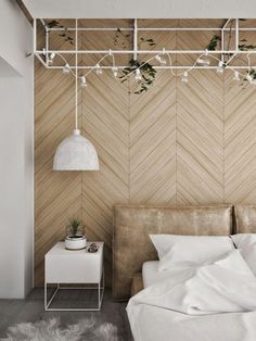 a bed with white sheets and pillows in a bedroom next to a wall mounted plant