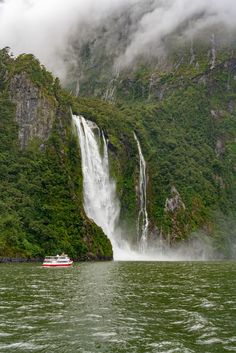 a boat is in the water near a waterfall