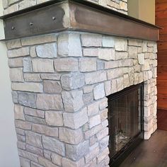 a stone fireplace in a living room with wood paneling on the wall behind it