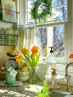 a kitchen counter topped with lots of dishes and vases filled with flowers next to a window