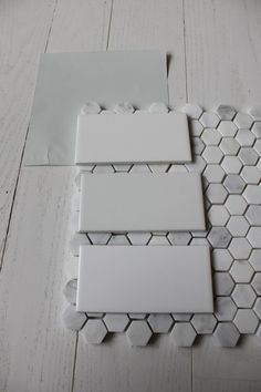 some white tiles are laying on top of each other in the middle of a wood floor