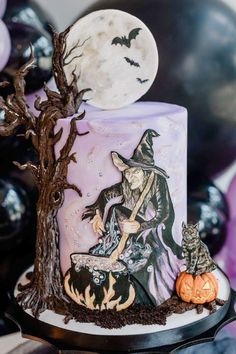 a decorated halloween cake with an image of a witch on top and pumpkins in the background