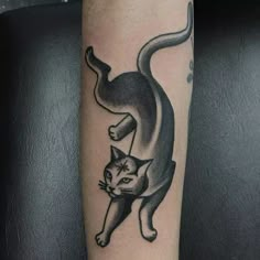 a black and white cat tattoo on the right arm with an arrow in it's tail