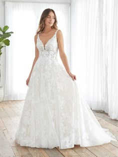 a woman in a white wedding dress standing on a wooden floor next to a window