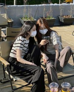 two women wearing face masks while sitting on chairs