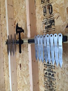 a bunch of tools hanging on the side of a wooden wall with screws attached to it