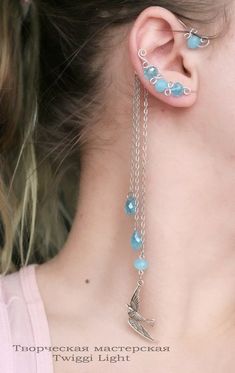 a close up of a person wearing some kind of ear chain with blue beads on it