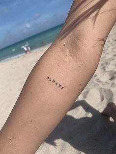 a person's arm with the word always written on it in black ink at the beach