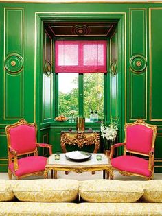 a living room with green walls and pink chairs