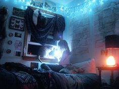 a woman is sitting on her bed in the dark with a light shining from behind