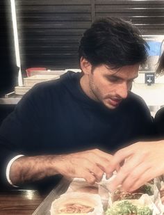 two people sitting at a table eating sandwiches