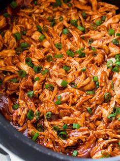 shredded chicken in a slow cooker with garnishes and green onions on top