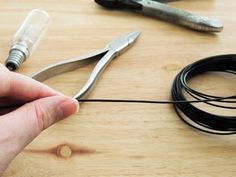 a pair of scissors are being held by someone's hand on a wooden table