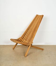 a wooden lounge chair sitting on top of a cement floor next to a white wall