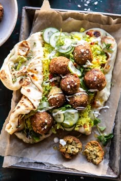 some meatballs and vegetables are on a piece of parchment paper with sauce drizzled over them