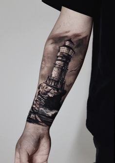 a man's arm with a lighthouse tattoo on the left forearm and right hand