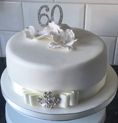 a white cake decorated with flowers and the number 60 on top is sitting on a table