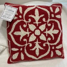 a red and white decorative pillow sitting on top of a bed