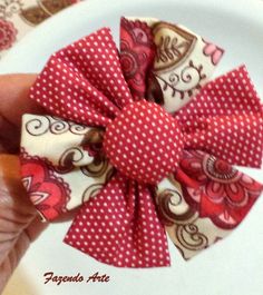 a person is holding a small red and white flower on a plate with polka dots