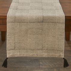 a table that has a brown and white checkered pattern on it with black tassels