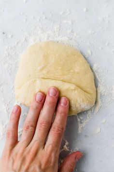 a person is kneading dough on top of a table with their hand over the dough