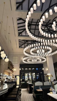 the interior of a restaurant with chandeliers hanging from the ceiling and black chairs