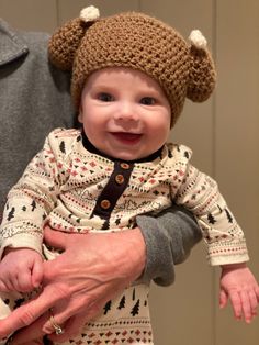 an older man holding a baby wearing a knitted hat