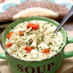 a green bowl filled with soup sitting on top of a wooden cutting board