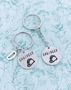 two keychains with the words engineer and engineer on them sitting next to each other