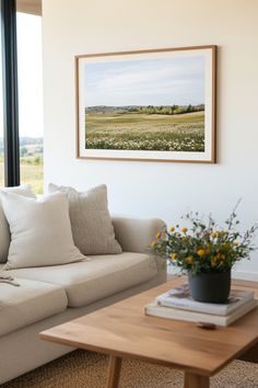 a living room filled with furniture and a painting hanging on the wall above it's windows