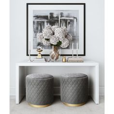 two stools with flowers and candles on them in front of a white console table