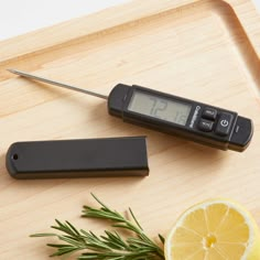 a digital thermometer sitting on top of a cutting board next to a lemon