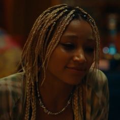 a woman with dreadlocks looking down at her cell phone while sitting in front of the camera