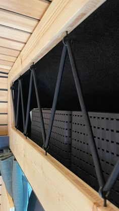 some sort of shelf that is made out of wood and has black plastic bins on it