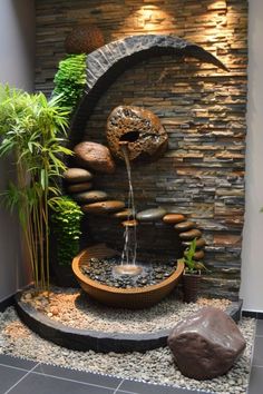 a water feature in the corner of a room with plants and rocks on it's sides