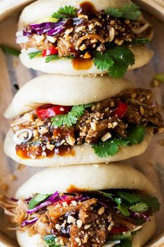 three buns filled with meat, vegetables and sauce