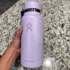 a hand holding a purple hydro flask water bottle