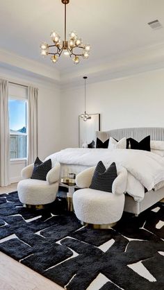 a bedroom with a large bed, two chairs and a chandelier hanging from the ceiling