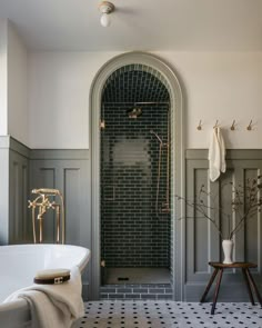 a bathroom with a black and white checkered floor, green tile walls and an arched doorway