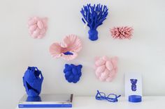 blue and pink objects are arranged on a white surface next to a pair of reading glasses