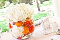 a vase filled with white and red flowers on top of a table next to wine glasses